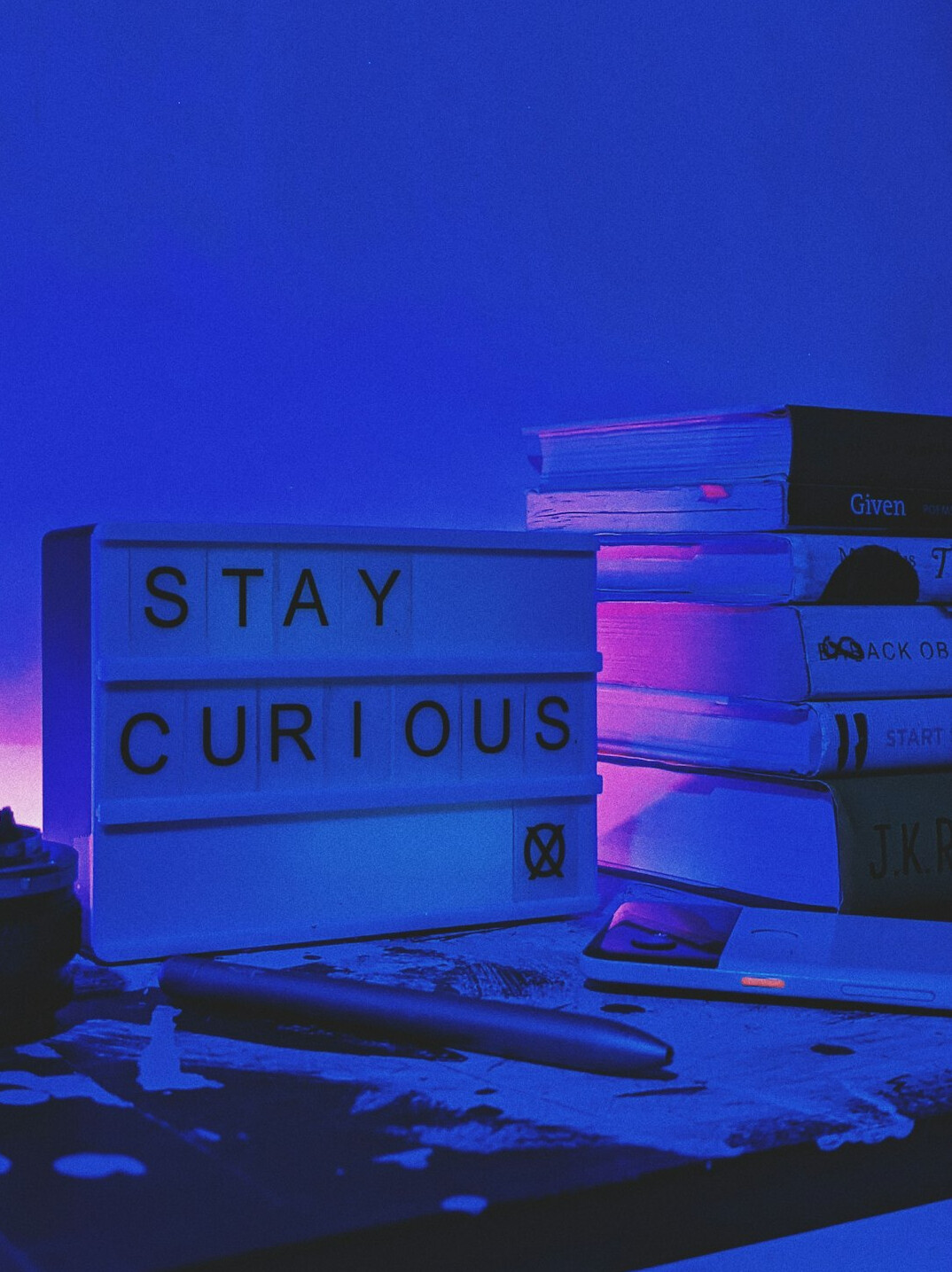 Stack of books next to an open laptop on a desk